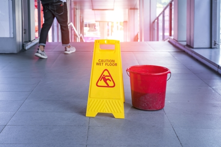 Caution wet floor sign next to a red bucket | Action Law Group