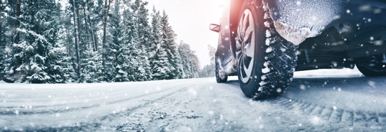 close-up of car tires driving on snowy road